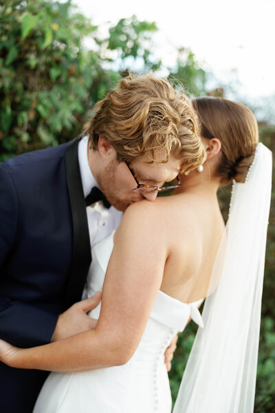 Candid couple kiss surrounded by lush greenery after Arkansas wedding