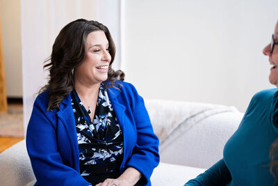 Dr. Chris Limone in a light blue blazer smiling and holding a book titled “Dream, Create, Manifest”