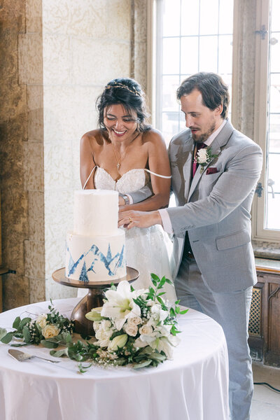 A refined moment as the bride and groom cut their elegant wedding cake during their reception at the iconic Fairmont Banff Springs Hotel in Banff National Park.