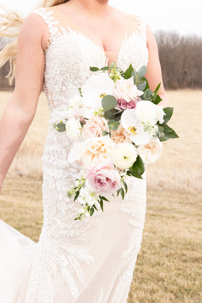 bride holding a bridal bouquet while standing in a field