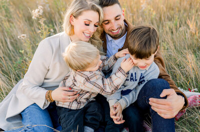 Family of four sitting together in a park in Calgary, AB.