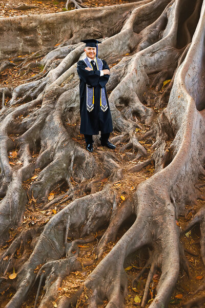 College graduate posing confidently on the roots of a banyan tree at Balboa Park in San Diego