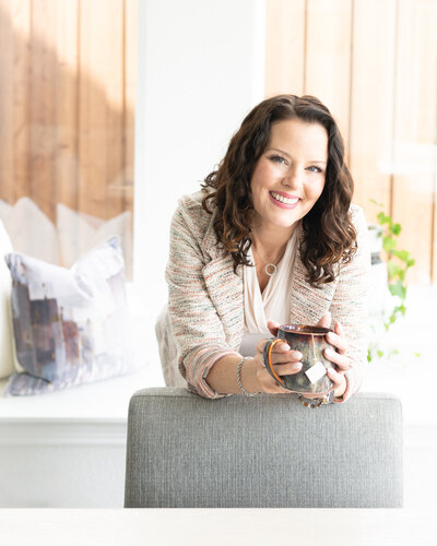 woman owned business owner leaning over a chair back drinking tea