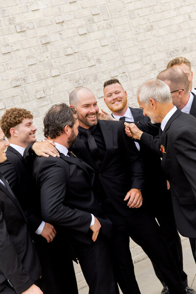 Cropped and slightly angled photo of groom in the middle of his groomsmen, as they all huddle around him and get excited about his upcoming ceremony in Raleigh, NC.