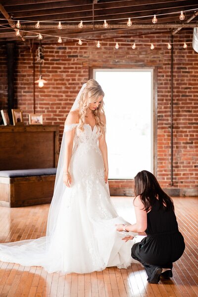 Photo assistant helping the bride adjust her wedding dress during bridal portraits