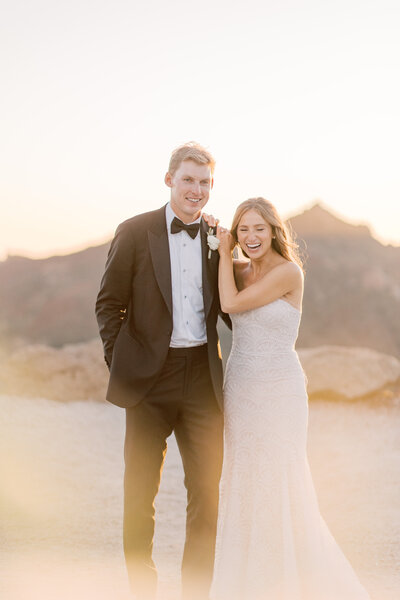 Brider and groom laughing atop of a mountain in malibu