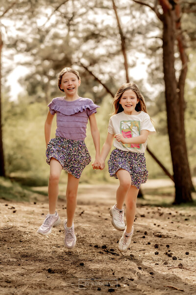 Twee zusjes huppelen samen door het bos bij Herperduin
