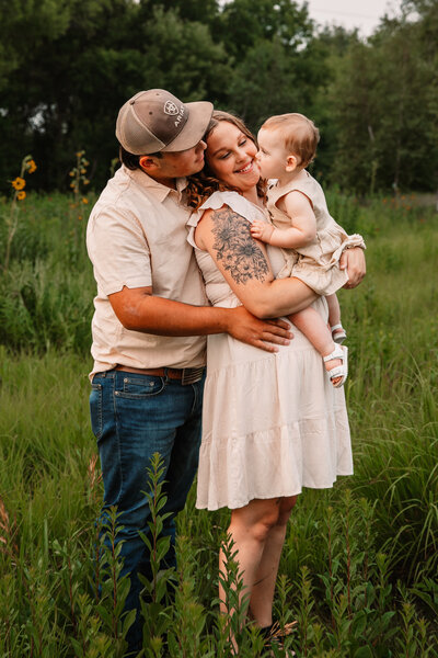 family of three snuggle in a field of sunflowers