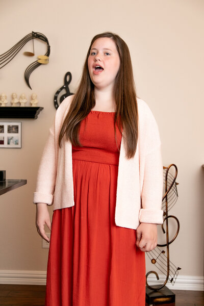 A student of Canchola Studio of Voice singing in a red dress.