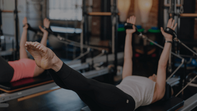 woman holding an extended crunch position on a pilates reformer 