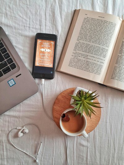 Open book, tea, cell phone, computer and a plant