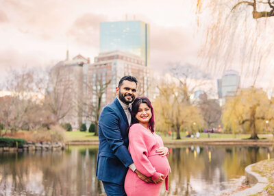 An Indian pregnant couple smiling  in the Boston Public Garden