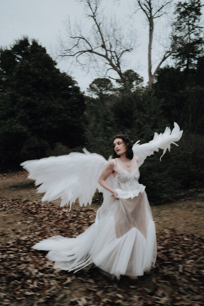 Photograph of girl in flowy white dress with large pair of wings running away