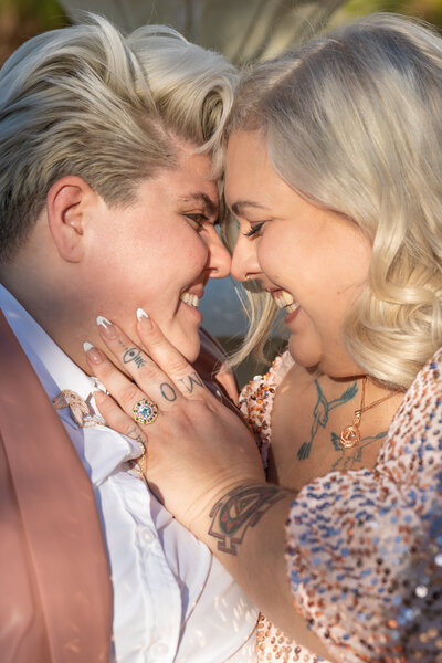 A couple standing face to face smiling as one touches the other's face