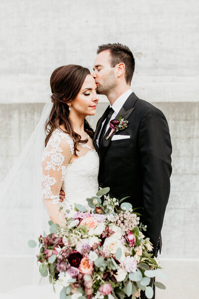 Groom kissing bride on her forehead after their wedding ceremony.