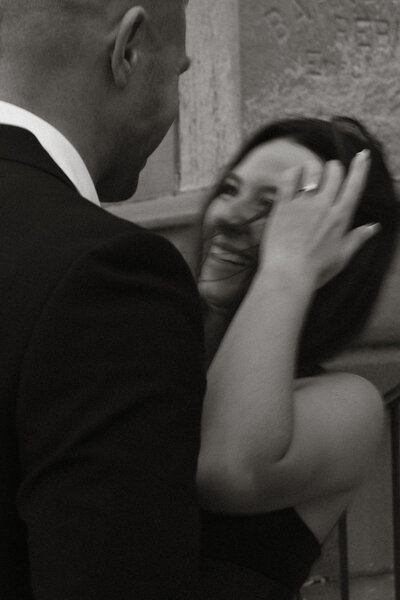 Black and white candid photo of a couple laughing together during their Michigan City engagement session near Washington Park Beach, captured by Rainstorm Photo & Video in a warm, documentary style.