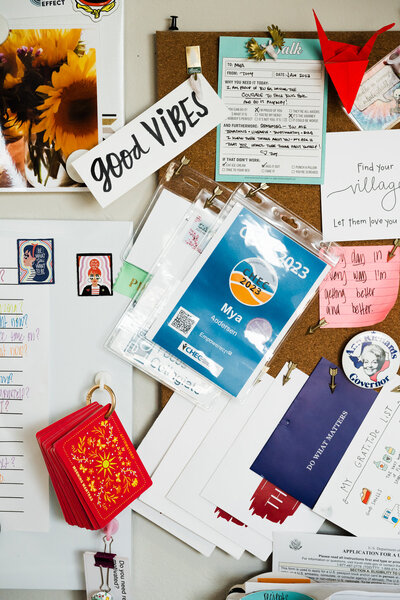 A cluttered corkboard with notes, badges, cards, a good VIBES sign, and a red origami crane—perfectly capturing the spirit of Mya Andersen’s Personalized Academic Life Coaching for College Success.