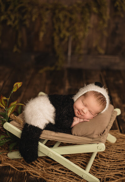 Baby Boy sleeping on a cot dressed in a cozy panda sleeper smiling sleeping for his Greater Toronto Newborn Photos.