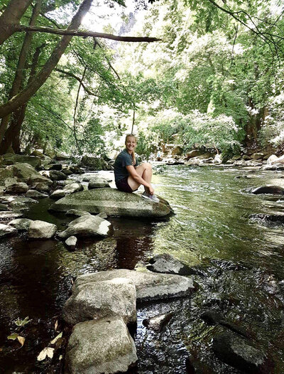 girl sitting on a big rock in a river