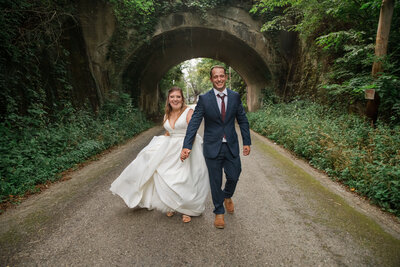 Laughing couple takes a stroll on an old road with a stone bridge