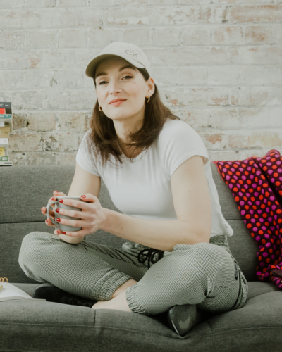 Ulrike Storch Welcome To Selling Circus  sitting on couch holding  a cup of tea