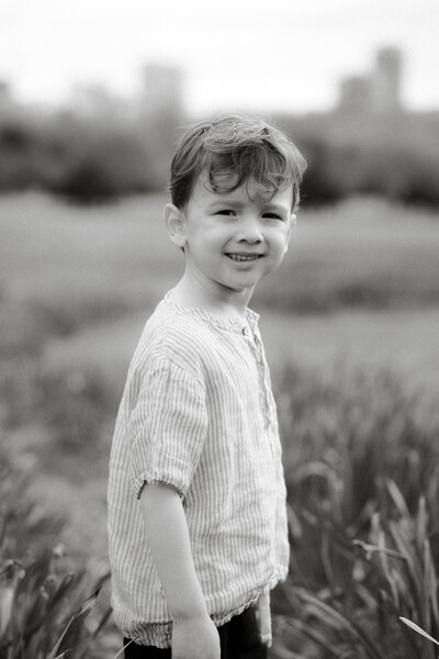 young boy smiling at camera in a field