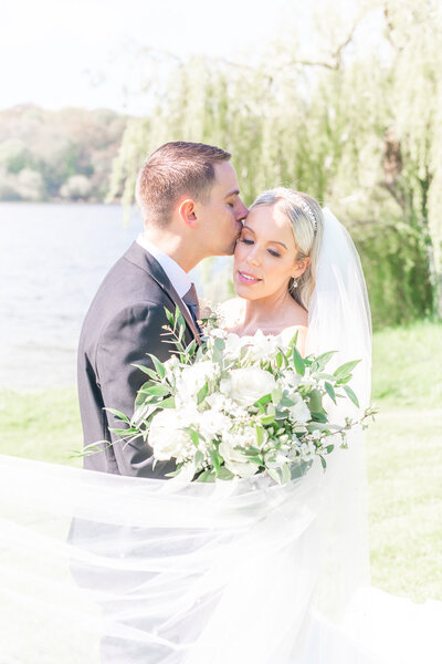 Bride and groom embracing in front of the lake at Combermere Abbey in Cheshire