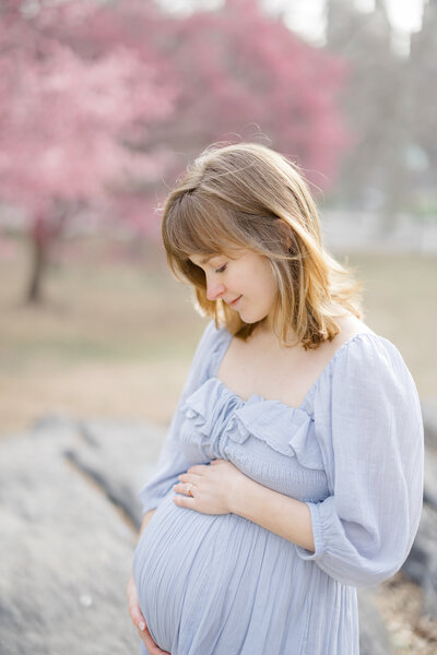 Woman holding pregnant belly in Central Park by NYC maternity photographer