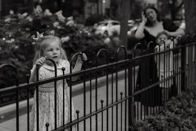 little girl climbs on fence as mom looks on during chicago family session