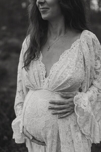 Svartvit närbild på magen på en gravid kvinna.