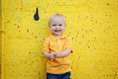 st-louis-mini-sessions-toddler-boy-in-yellow-shirt-on-yellow-wall