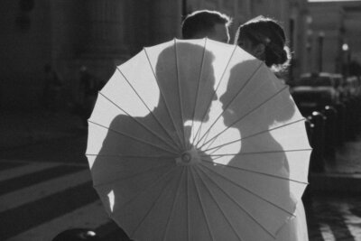 Bride and groom hiding behind a parasol with the sunlit illuminating their silhouette in Washington DC, captured by Andrea-Marie Photography 