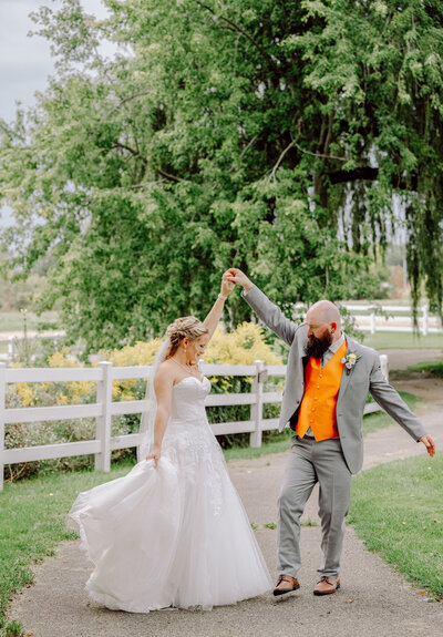A couple dancing by a white fence at their Michigan wedding captured by a West Michigan wedding photographer