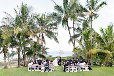 A wedding ceremony on a lawn with the ocean in the background 
