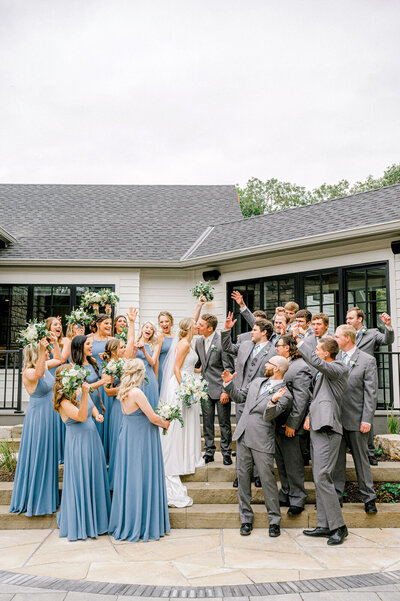 bride and groom kiss while wedding party cheers them on near Omaha