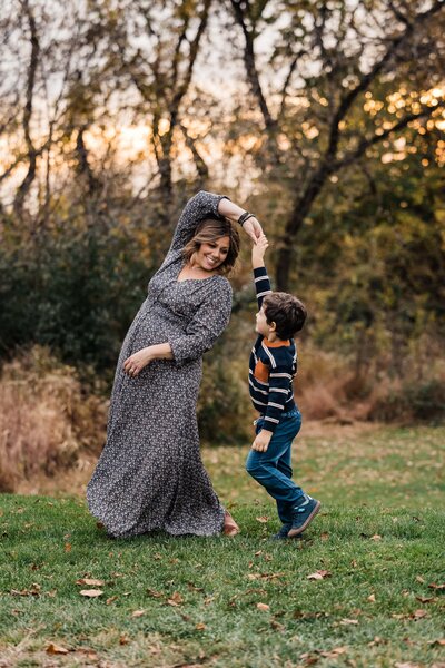 A joyful moment between a mother and her son dancing outdoors in the autumn, captured by a talented family photographer Pittsburgh PA.