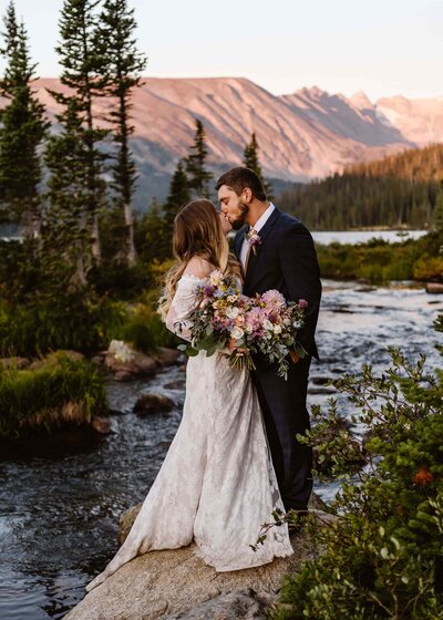 Couple kisses at sunrise at an alpine lake with colorado adventure elopement photographer Alpine Vows