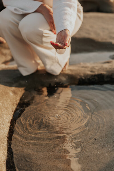 Water dripping from hand over small  tidal pool