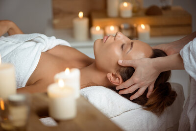 Client receiving a calming head and scalp massage in a softly lit room with candles.