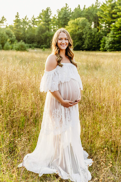 stunning mom to be  in a lace gownholding her baby bump  captured by Ashley Kalbus Photography