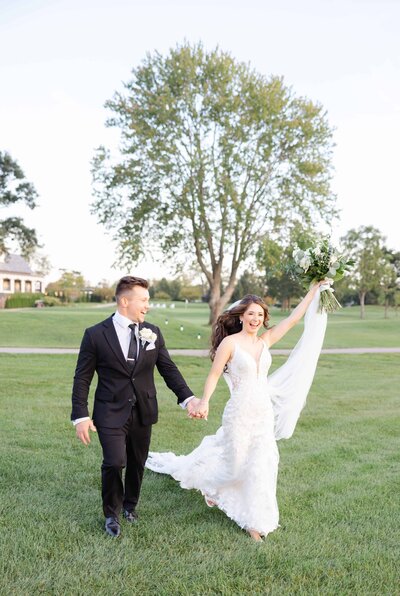 Sunset wedding portrait of bride and groom running on the golf course at Hinsdale Golf Club.