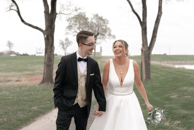 bride and groom holding hands walking on path