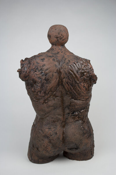 A ceramic bust of a feminine body with various cracks and brick textures