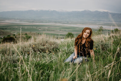 Jackson hole wedding  sitting in a grassy field with the mountains in the distance