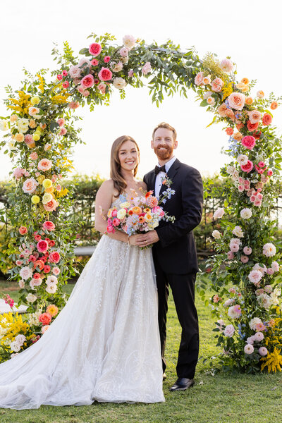 modern wedding portrait with colorful flower arch in backdrop