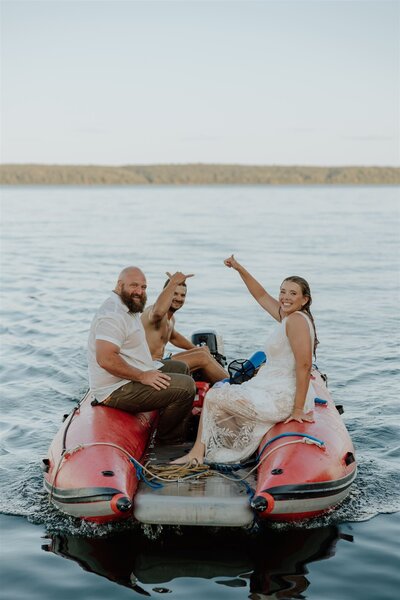 bride and groom sitting on a red raft boat after jumping into a lake