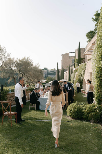 Black and white action shot of wedding guests clinking glasses during a Welcome Dinner at Bastide de Pierres