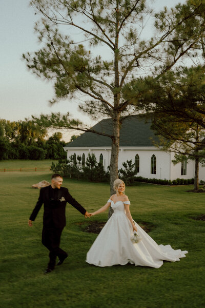 okc wedding photographer documents couple walking hand in hand at their wedding at the springs
