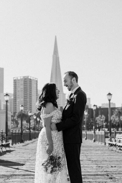 newlyweds pose on city boardwalk