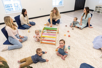 Group of babies playing in a circle while their moms watch